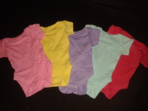 Five baby vests, assorted colours.
